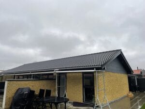 Enkelt familiehus med sort tegltag og terrasse