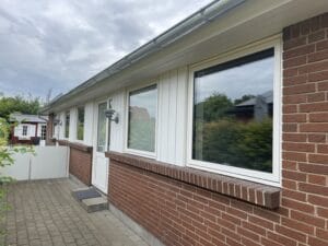 Rødt murstenshus med hvide vinduer og dør